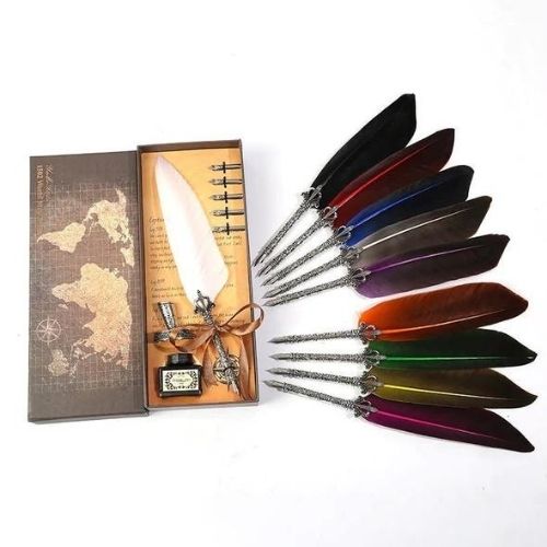 Set of colorful feather quills with an inkwell and map-themed box on a white background